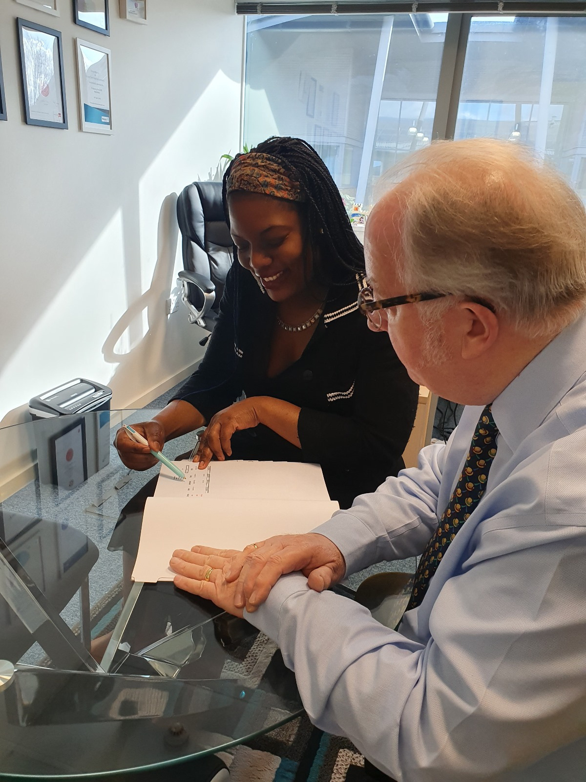 Dora Ngoma discussing tax compliance paperwork with a client in a bright office.