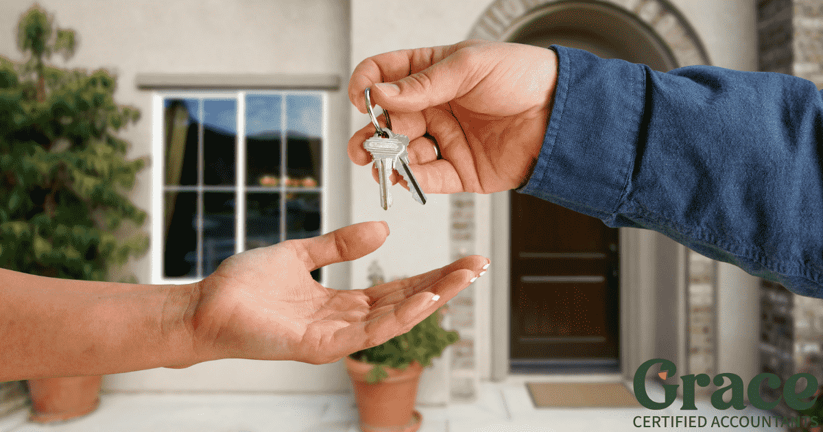 One person handing over house keys to another in front of a residential home – symbolising property gift or family transfer